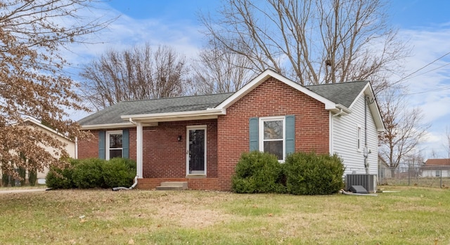 view of front of property featuring roof with shingles, brick siding, a front lawn, and central AC unit