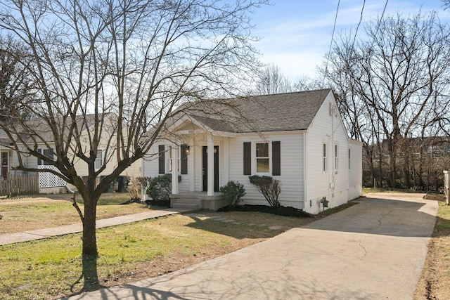 bungalow-style house with a shingled roof, a front lawn, and fence