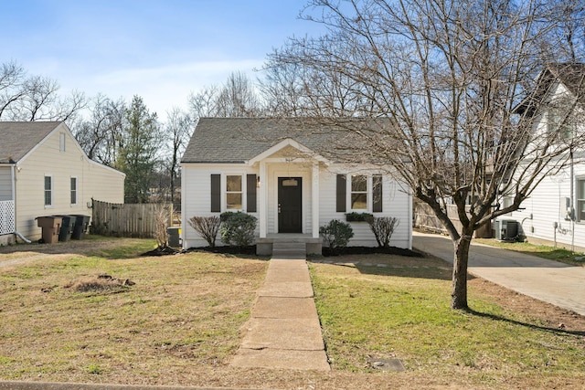 bungalow-style house featuring a shingled roof, fence, a front lawn, and central AC