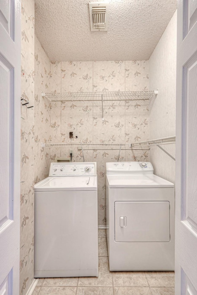 laundry room featuring visible vents, laundry area, light tile patterned flooring, a textured ceiling, and independent washer and dryer