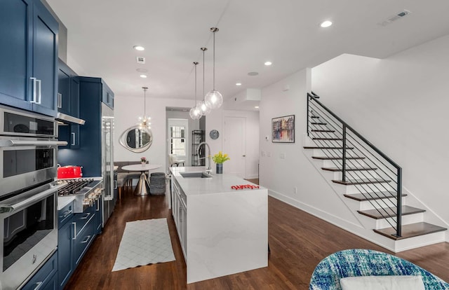 kitchen featuring stainless steel double oven, dark wood-type flooring, a sink, visible vents, and blue cabinetry