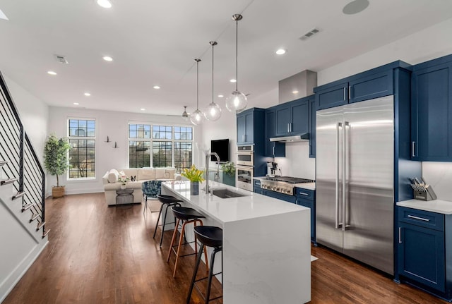 kitchen with appliances with stainless steel finishes, a breakfast bar area, light countertops, blue cabinetry, and a sink