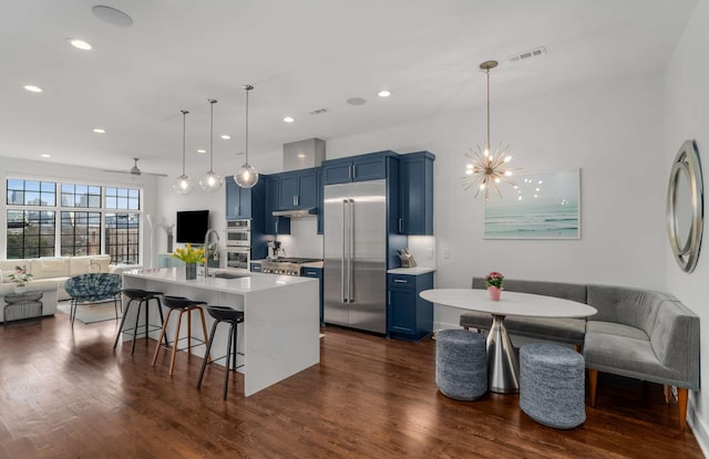 kitchen featuring a breakfast bar area, visible vents, appliances with stainless steel finishes, open floor plan, and blue cabinets