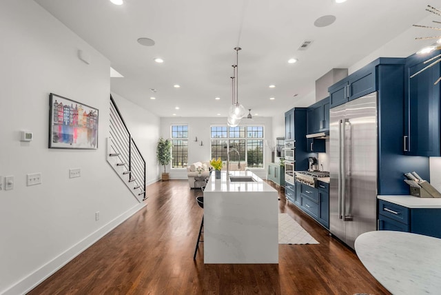 kitchen with stainless steel appliances, blue cabinetry, dark wood-style flooring, and a sink