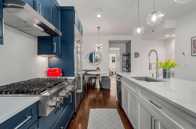 kitchen with blue cabinets, wall chimney range hood, light countertops, and a sink