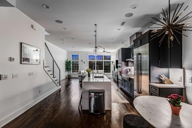 kitchen featuring dark wood-style floors, stainless steel appliances, light countertops, a sink, and dark cabinetry