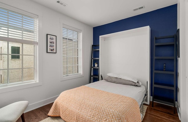 bedroom featuring baseboards, visible vents, and wood finished floors