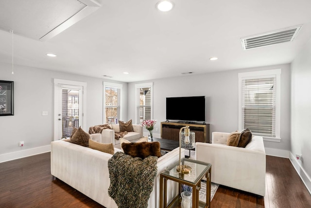 living area featuring attic access, visible vents, dark wood finished floors, and baseboards