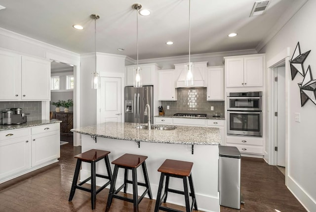 kitchen featuring dark wood-style flooring, stainless steel appliances, visible vents, ornamental molding, and a sink