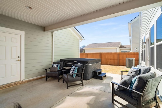 view of patio / terrace with fence private yard, a hot tub, and an outdoor living space