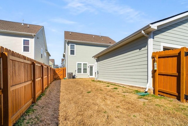 back of property featuring central AC, a lawn, and a fenced backyard