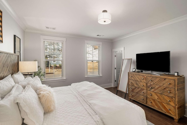 bedroom with dark wood-style floors, ornamental molding, visible vents, and baseboards