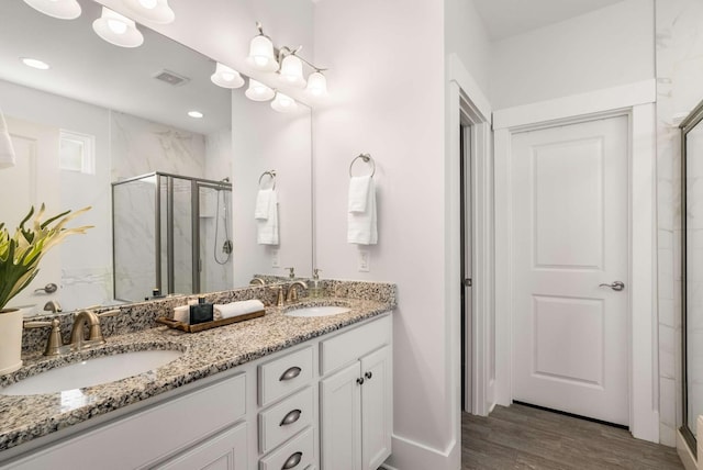 full bathroom featuring visible vents, a sink, a marble finish shower, and wood finished floors