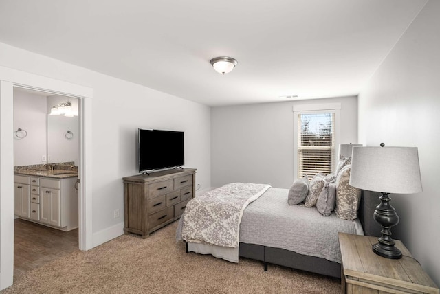 bedroom with ensuite bath, baseboards, and light colored carpet