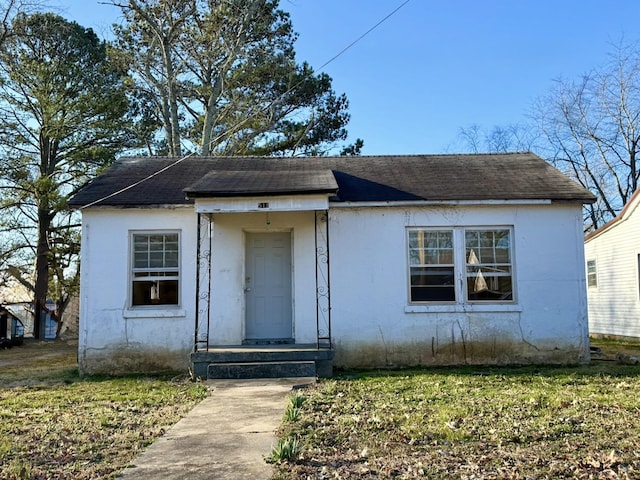 bungalow-style home featuring a front yard and roof with shingles