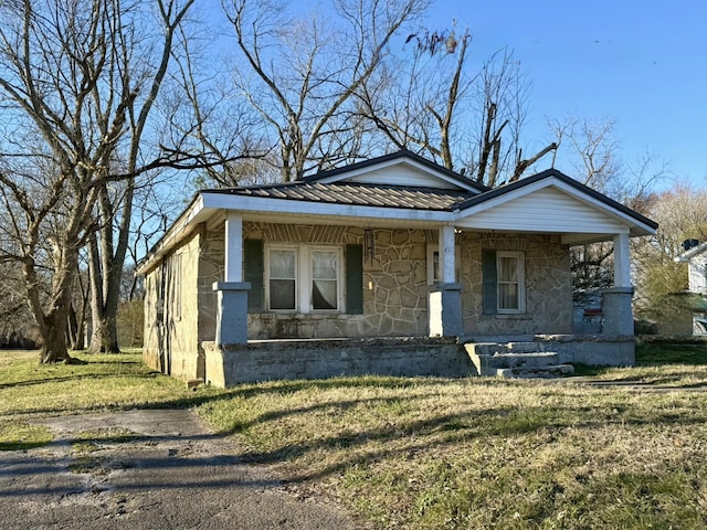 bungalow featuring a porch, stone siding, metal roof, and a front lawn