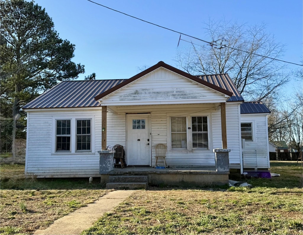 bungalow featuring a front yard, covered porch, and metal roof