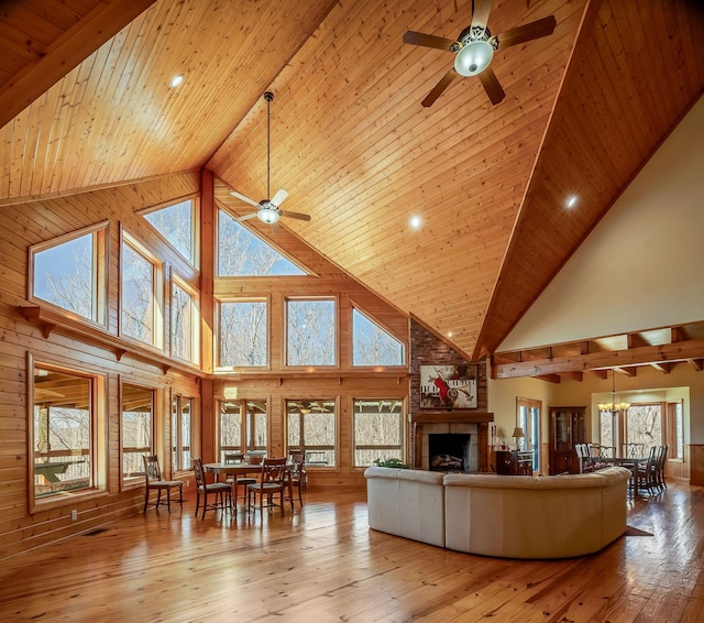 living area with a fireplace, wood-type flooring, wood ceiling, wood walls, and ceiling fan with notable chandelier