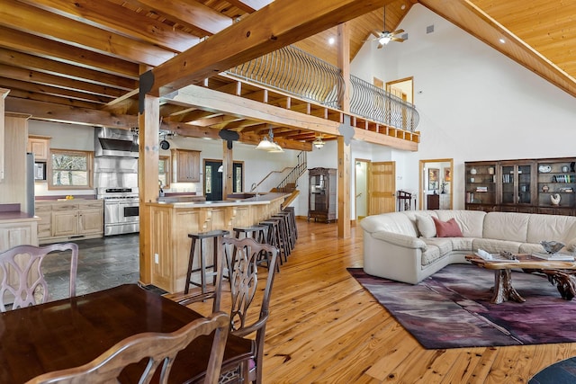 living area featuring ceiling fan, stairway, dark wood-style flooring, high vaulted ceiling, and beam ceiling