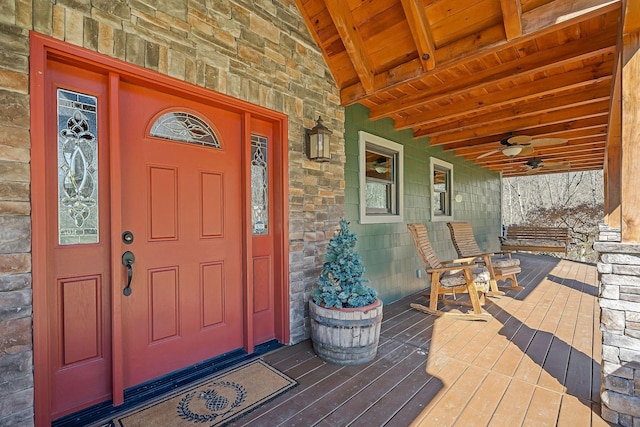 view of exterior entry with stone siding and a porch