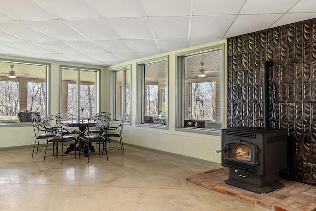 sunroom / solarium featuring a drop ceiling and a wood stove