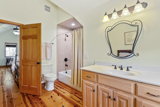 bathroom featuring toilet, visible vents, vanity, wood-type flooring, and shower / bath combination with curtain