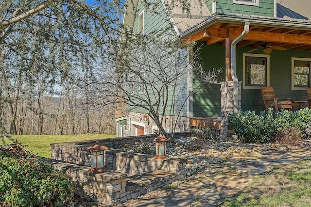 view of side of home featuring covered porch, metal roof, and ceiling fan