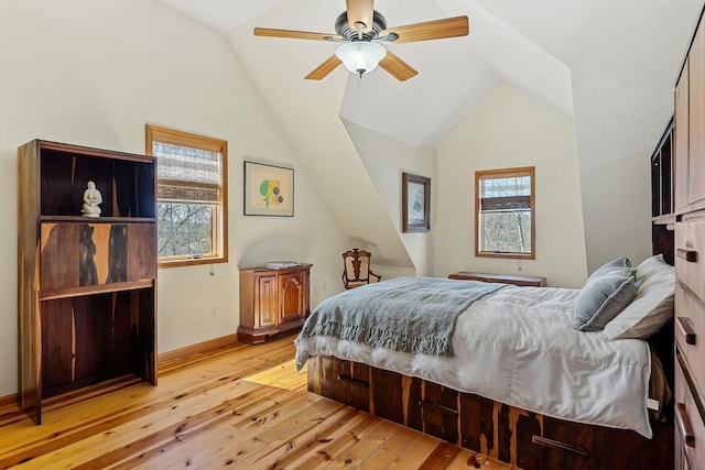 bedroom featuring vaulted ceiling, multiple windows, and light wood-style flooring