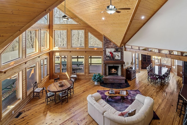 living area with wood ceiling, a brick fireplace, a healthy amount of sunlight, and hardwood / wood-style flooring