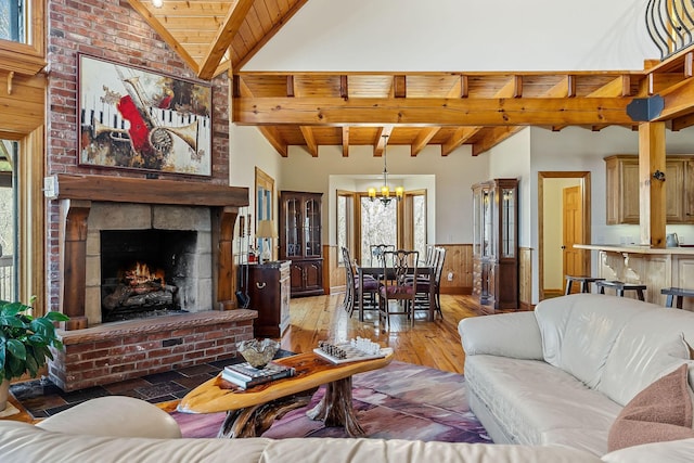 living area with a notable chandelier, lofted ceiling with beams, wood ceiling, wainscoting, and light wood-type flooring