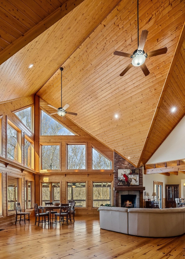 living area with wooden ceiling, hardwood / wood-style flooring, ceiling fan, vaulted ceiling with beams, and a fireplace