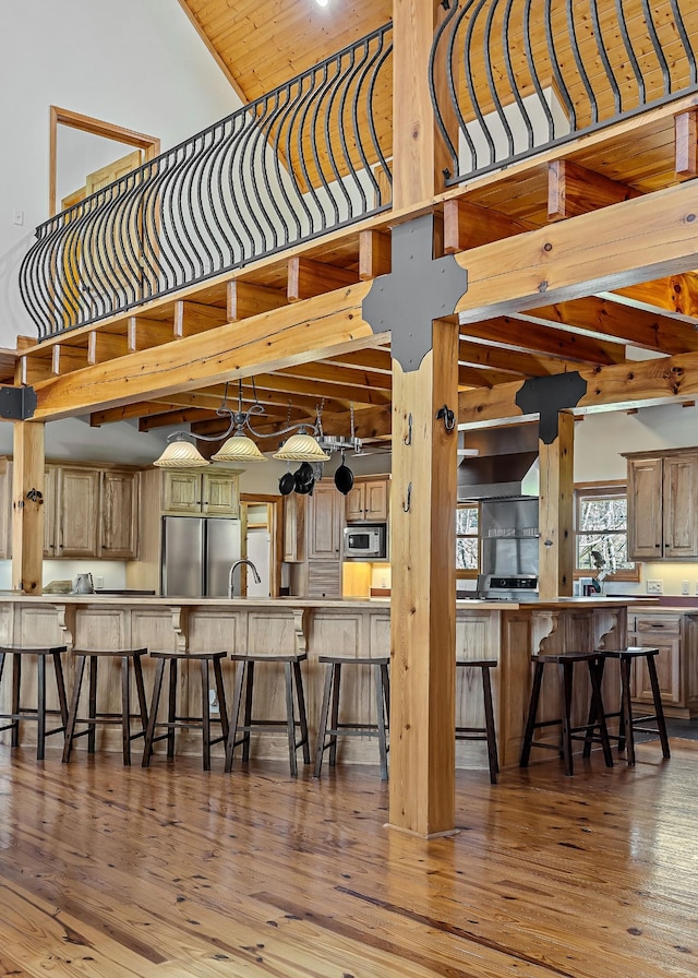 kitchen with a kitchen bar, a high ceiling, stainless steel appliances, and wood finished floors