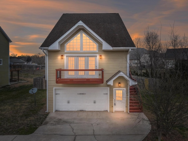 traditional-style house featuring a garage, a shingled roof, concrete driveway, and a yard