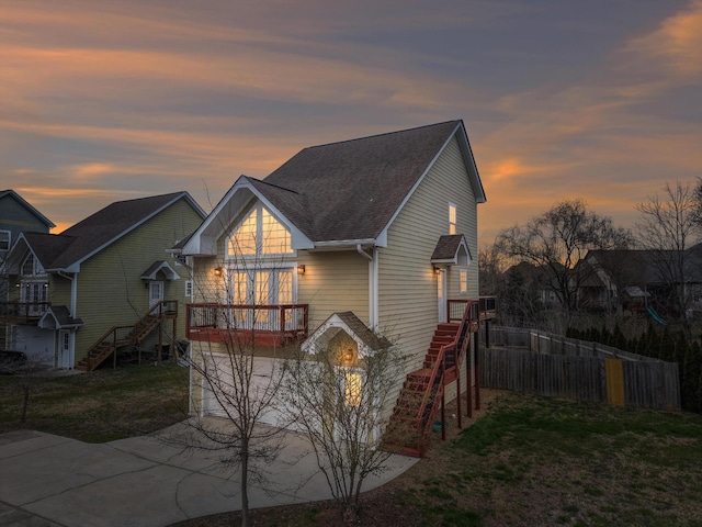 exterior space with stairway, roof with shingles, a front yard, and fence