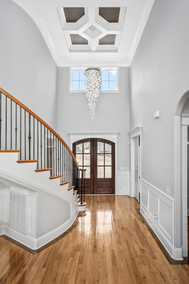 foyer entrance with stairs, arched walkways, wood finished floors, and french doors