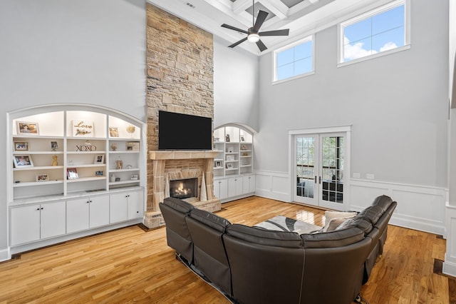 living area with light wood-type flooring, a fireplace, a wealth of natural light, and wainscoting