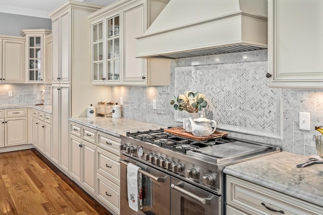 kitchen featuring double oven range, premium range hood, light wood finished floors, and cream cabinetry