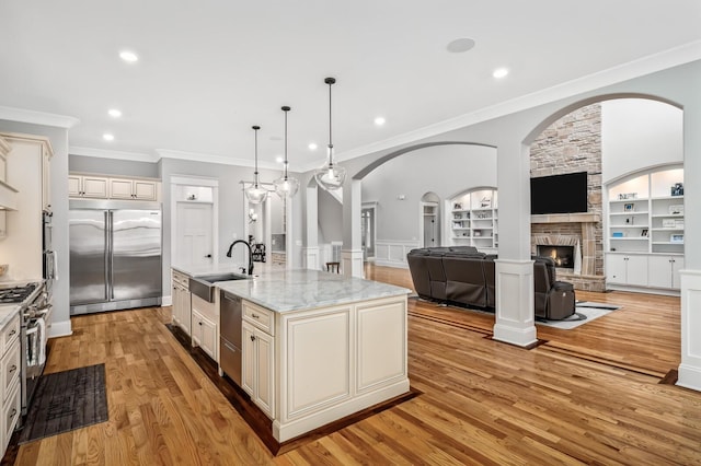 kitchen featuring built in features, cream cabinetry, a fireplace, light wood-style flooring, and high quality appliances