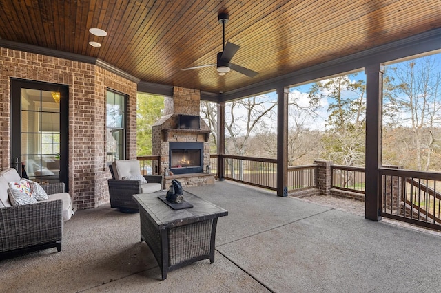 view of patio / terrace with ceiling fan and an outdoor living space with a fireplace