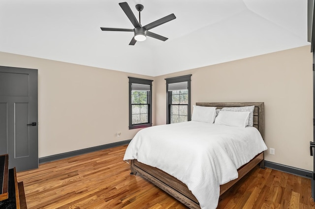 bedroom with ceiling fan, baseboards, vaulted ceiling, and wood finished floors