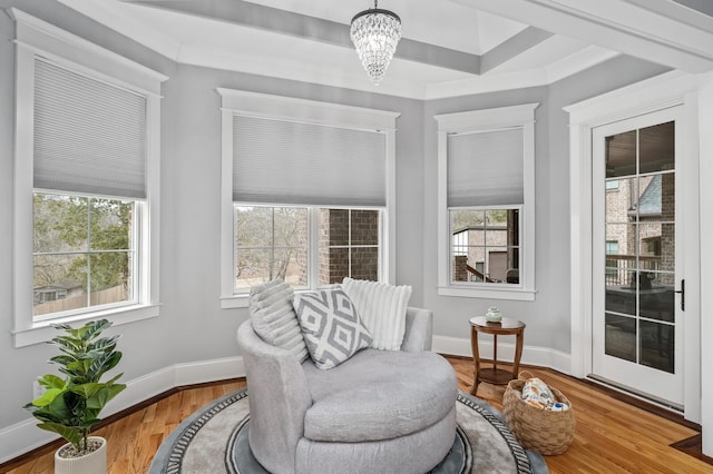 living area featuring baseboards, plenty of natural light, a chandelier, and wood finished floors