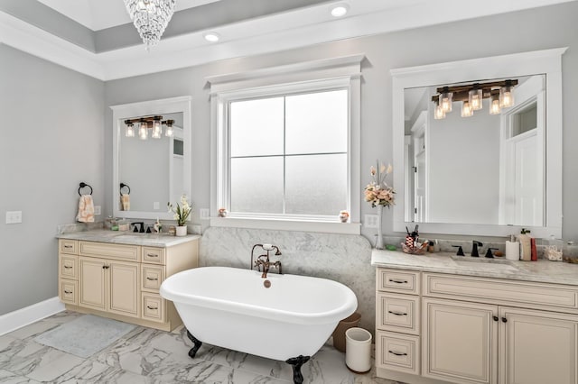 full bath featuring marble finish floor, two vanities, a sink, and a soaking tub