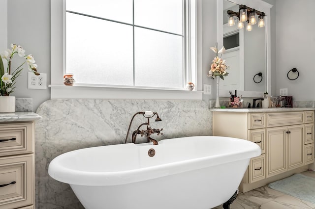 full bath with marble finish floor, a freestanding bath, and vanity