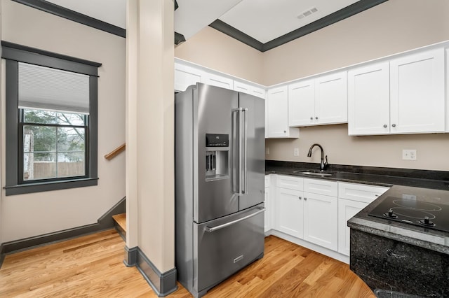 kitchen featuring black electric stovetop, white cabinetry, a sink, and stainless steel fridge with ice dispenser