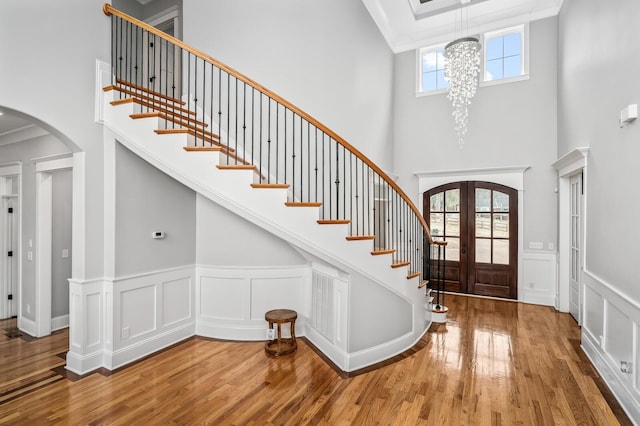 foyer featuring stairs, arched walkways, french doors, and wood finished floors