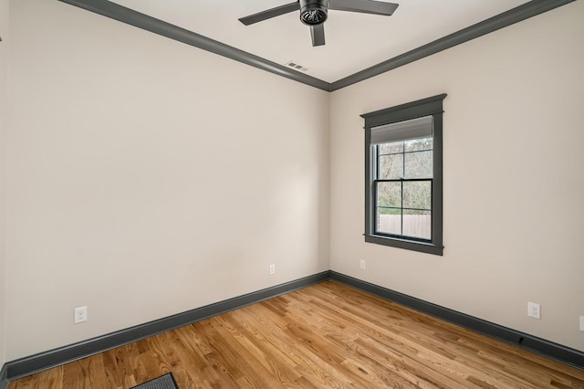 spare room featuring baseboards, visible vents, light wood-style flooring, ceiling fan, and crown molding