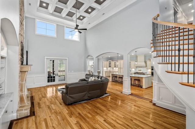 living area with ceiling fan, light wood finished floors, stairway, and plenty of natural light