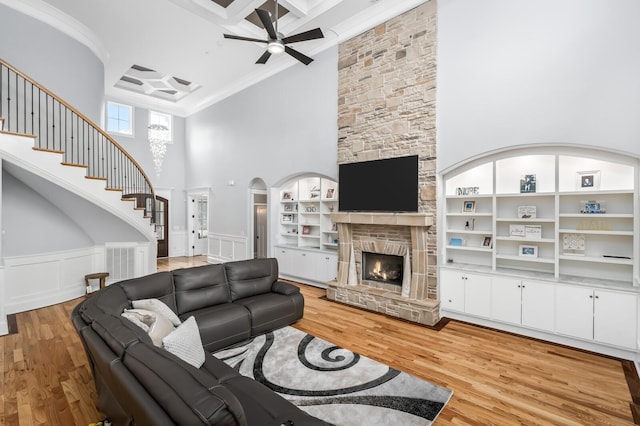 living room featuring a fireplace, visible vents, light wood-style floors, ornamental molding, and stairway