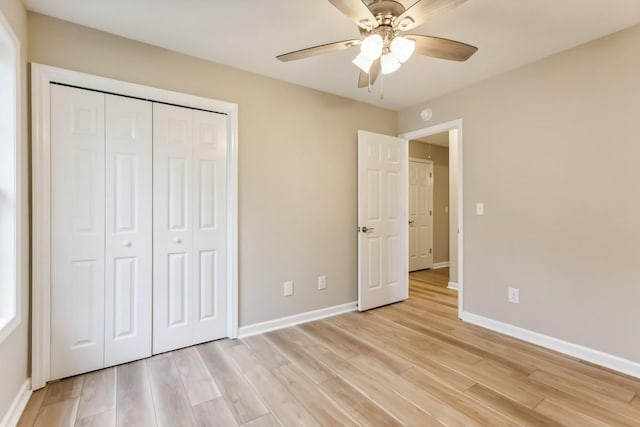 unfurnished bedroom with light wood-type flooring, a ceiling fan, baseboards, and a closet