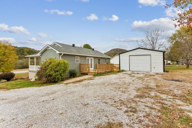 view of front facade featuring a garage, driveway, an outdoor structure, and a wooden deck